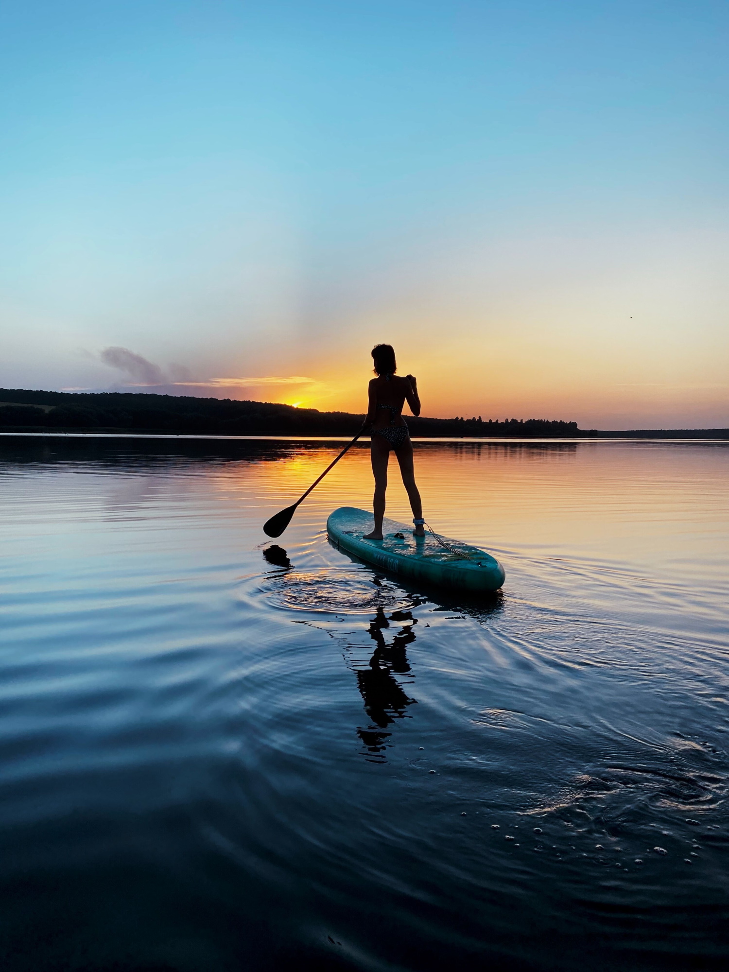 A woman paddleboarding during sunset in Shelter Island, New York.